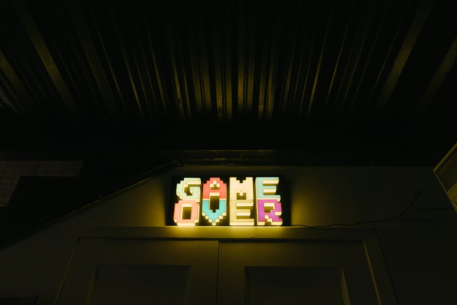 Glowing neon sign with pixelated Game Over text in a dark arcade setting.