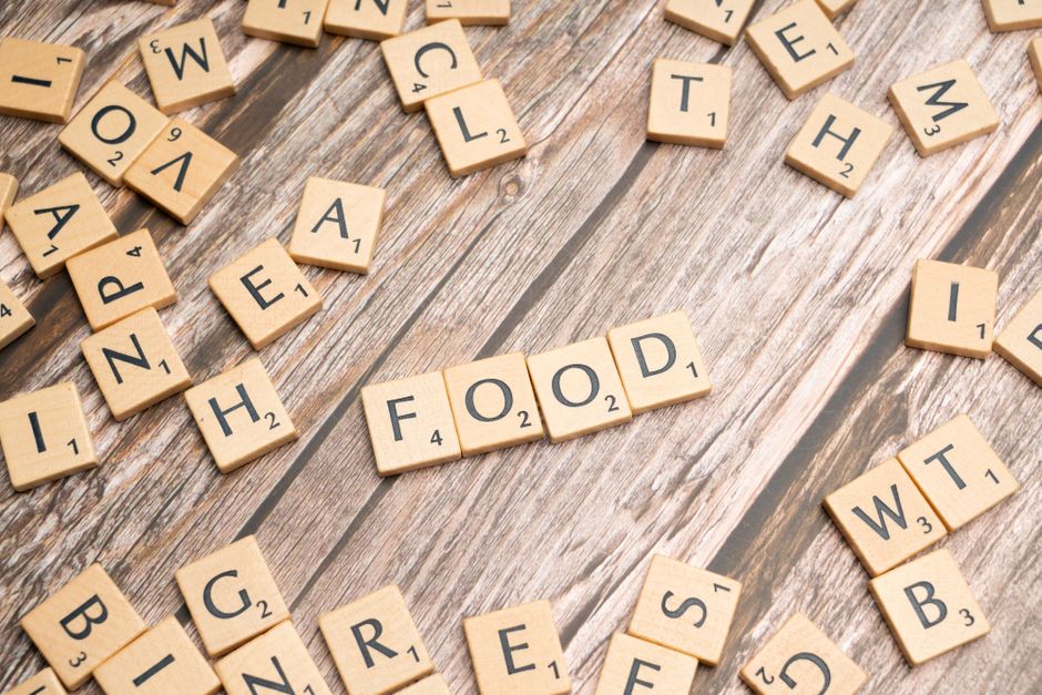 Wooden letter tiles spelling 'food' arranged on a rustic wooden surface, depicting culinary themes.
