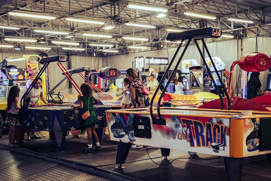 Children and adults enjoy air hockey games in a lively indoor arcade setting.