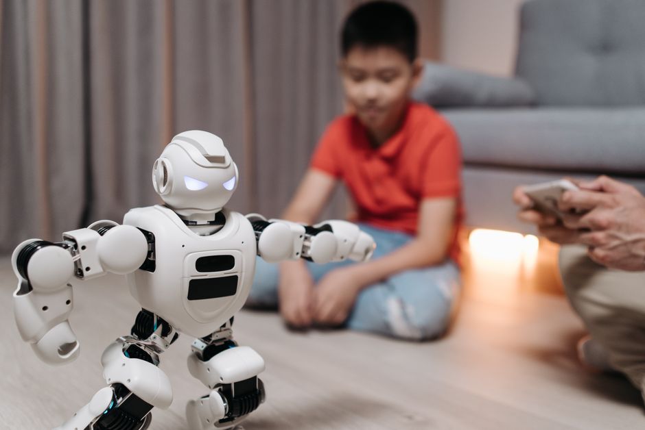 A young boy interacts with a programmable robot in a cozy living room setting.