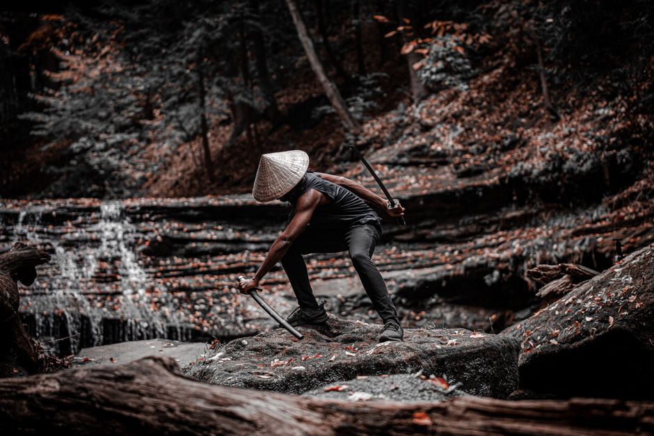 Dramatic scene of a samurai wielding swords on a forest rock, exuding dynamic and intense vibes.