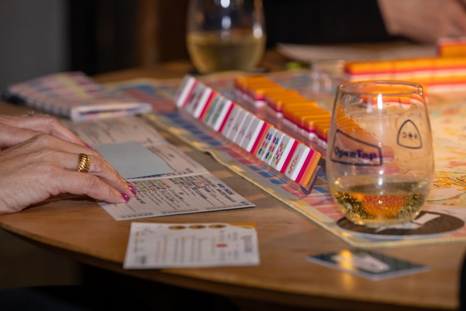 Engaging game night scene with friends playing mahjong and enjoying drinks. Perfect social moment.