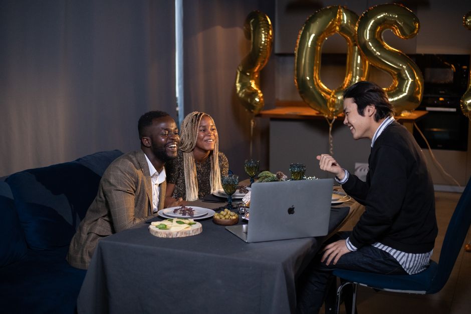 Friends enjoying a virtual New Year party with food and decorations.