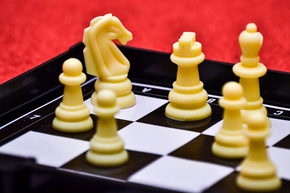 Close-up view of a chessboard with yellow pieces poised for strategic moves.