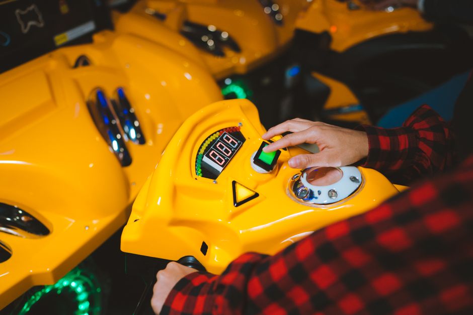 Close-up of a person playing an arcade game with a yellow console and colorful lights.